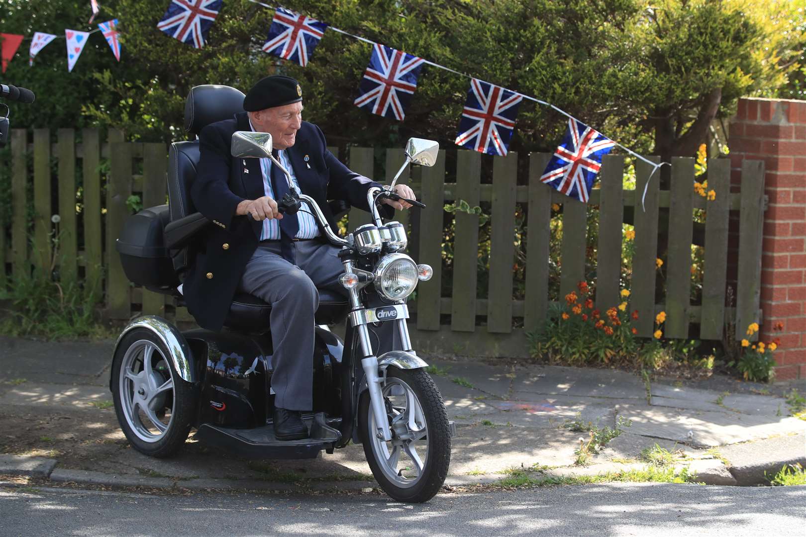 Ralph Harvey, 89, sits on a mobility scooter as he joins in his street’s celebrations in Duncan Avenue, Redcar (Owen Humphreys/PA)