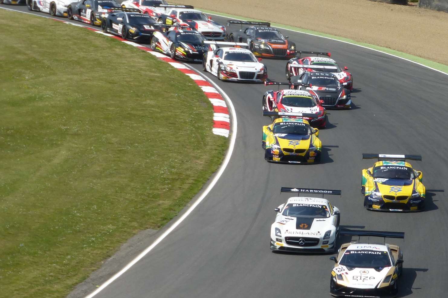 The field piles into Paddock Hill Bend at the start of the feature race. Picture - Joe Wright