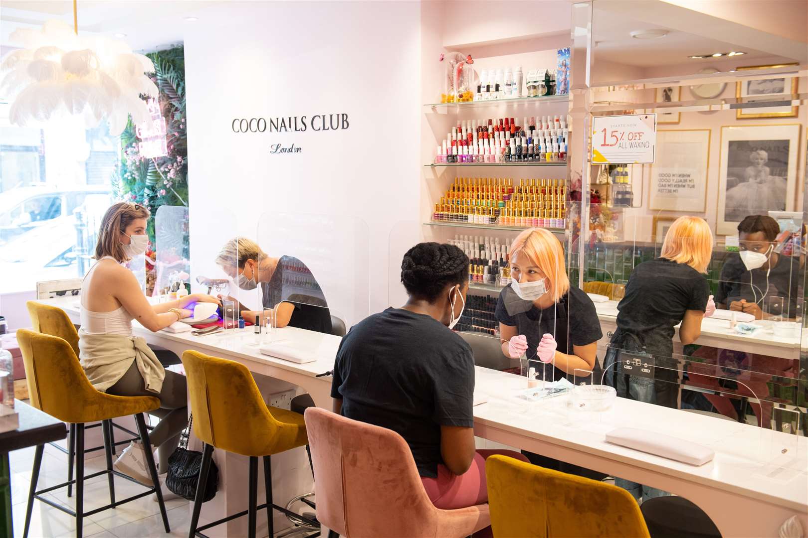 Customers observe social distancing behind screens at Coco Nails Club in London (Dominic Lipinski/PA)