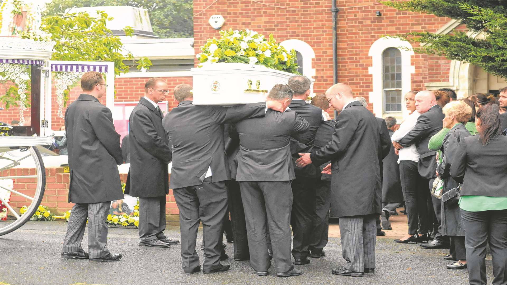 The pallbearers carry the coffin into St John Fisher Church