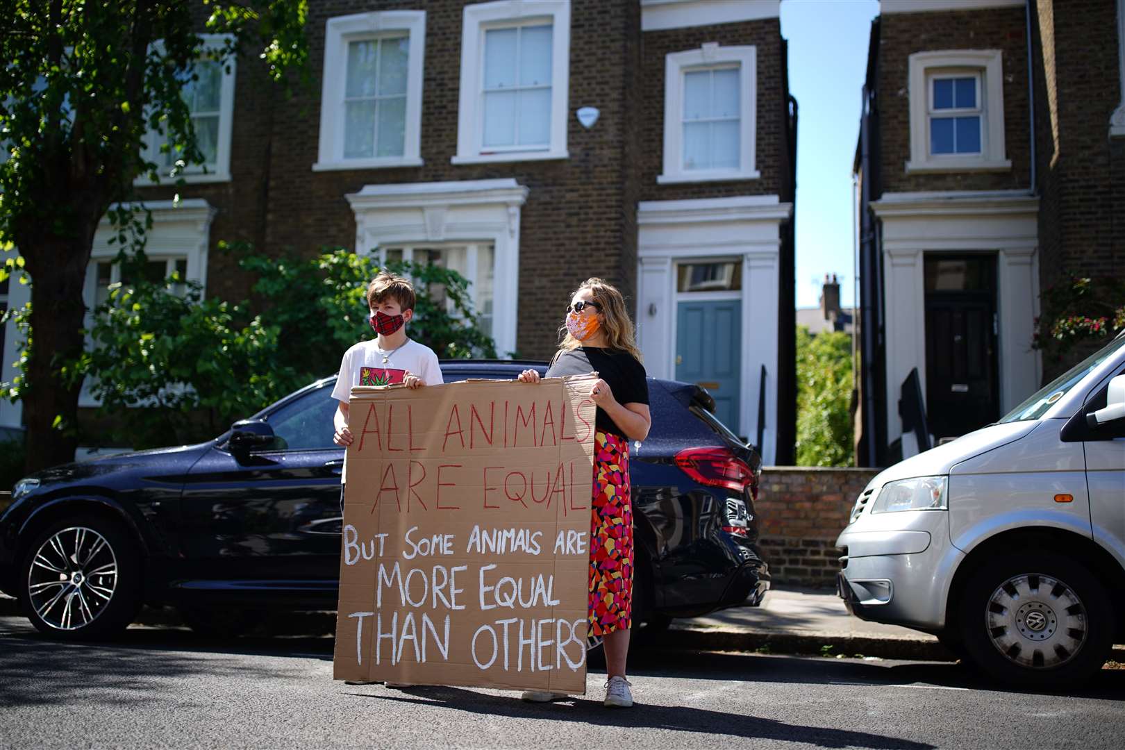 Protesters hold a sign with a quote from George Orwell’s Animal Farm outside the north London home of Dominic Cummings (Aaron Chown/PA)