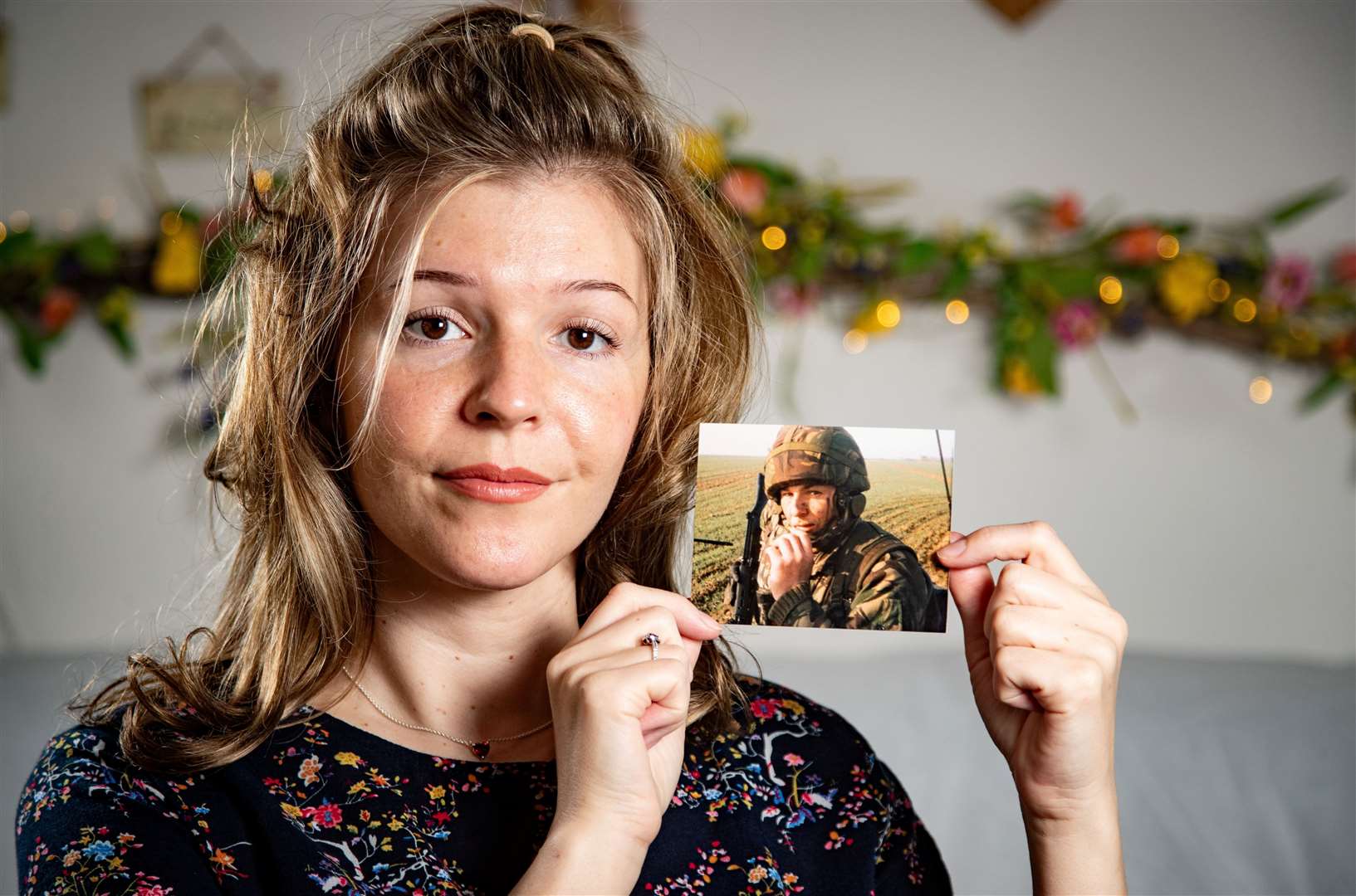 Stephanie holding up a photo of Mark whilst he was Staff Sergeant in the Royal Artillery, taken in Northern Ireland. Picture: SWNS