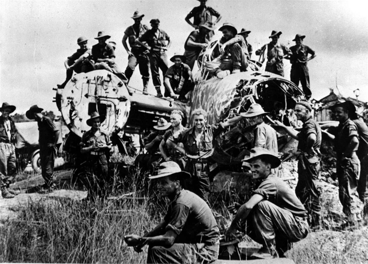 Members of the battalion from the Australian 9th Division climb over a wrecked Japanese bomber abandoned on the edge of the strip in Borneo (PA)
