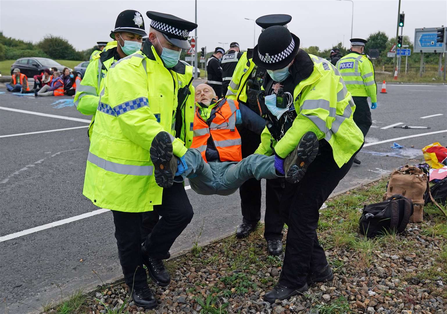 Police officers carry away a protester who had glued himself to the highway at a slip road at junction four of the A1(M), near Hatfield (Steve Parsons/PA)