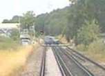 A car going over the crossing as the train approaches.