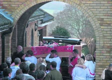 Draped in a Liverpool FC flag, the coffin of Alan Wallis is carried into Barham Crematorium