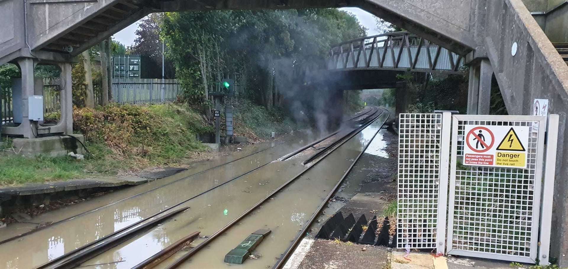 Smoke can be seen rising from the flooded tracks at Kemsely train station. Picture: Alex Matthews