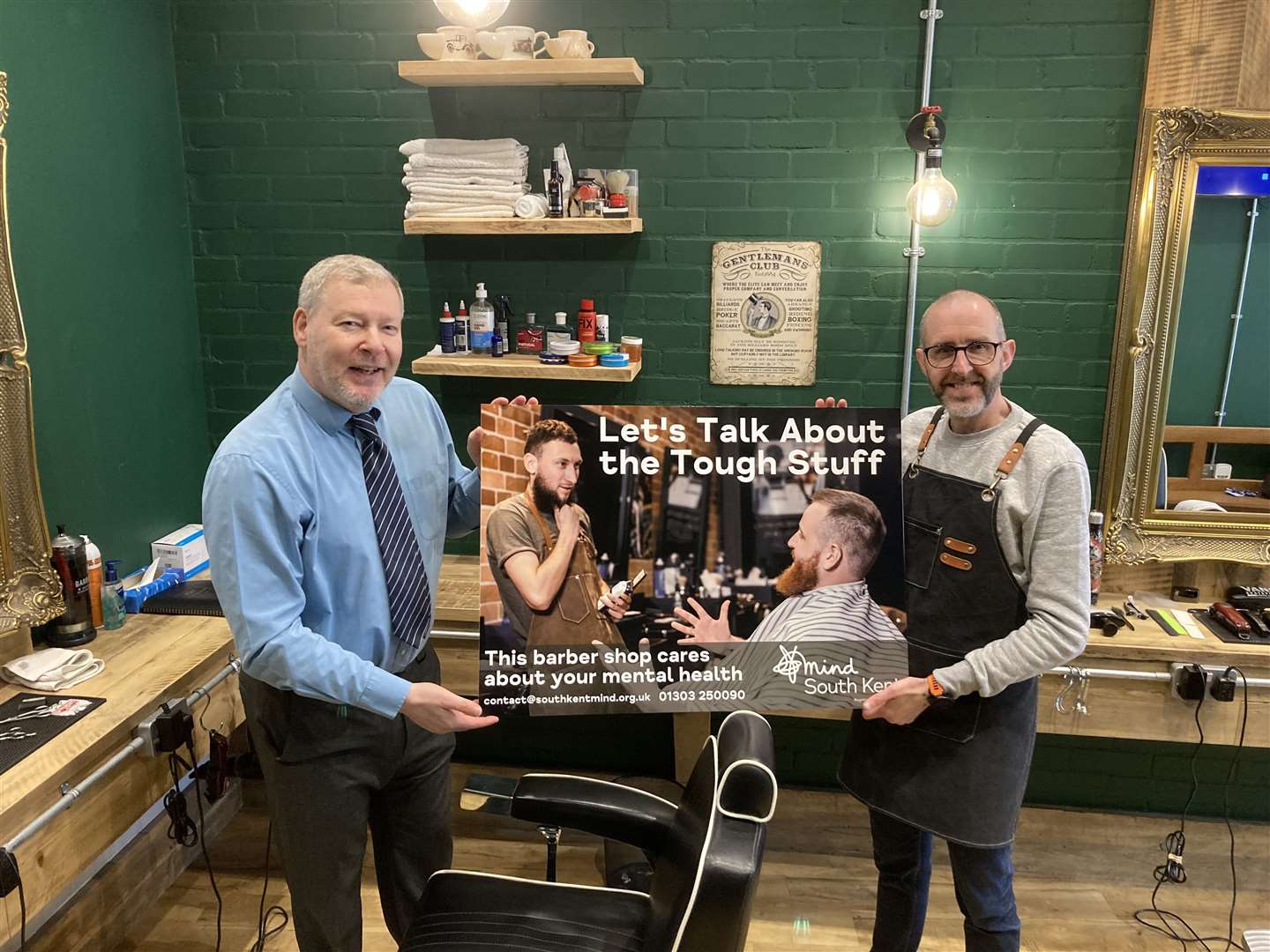 Simon Dolby from South Kent Mind, left, with barber Daniel Baker, holding the campaign poster. Picture: South Kent Mind