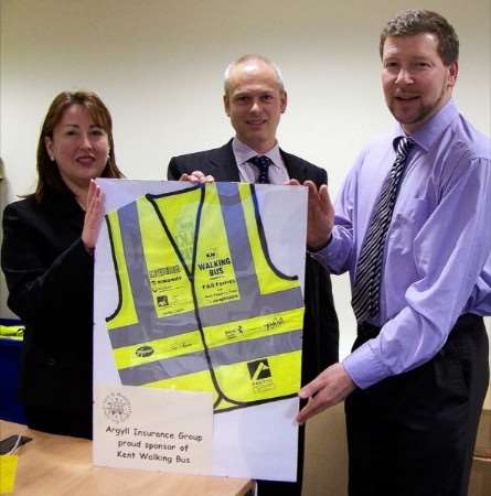 Jane Lawrence and Gareth Roberts, of Argyll Insurance, are presented with a framed tabard by Simon Dolby, of the KM Walk to School programme