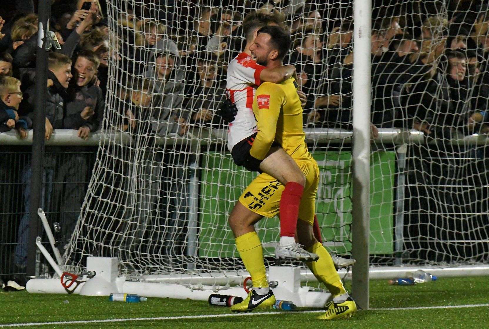 Sheppey goalkeeper Aiden Prall picks up penalty shoot-out winner Jacob Lambert. Picture: Marc Richards