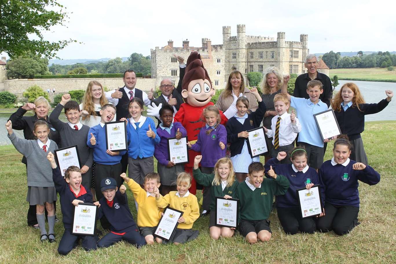 All winners of the KM "Walk to School Challenge" with their certificates at Leeds castle with Sponsors from left, Margaret Brook (IMP), Hannah Lawrence (Leeds Castle), David Cavender and Matt Trusty (Spec Savers), Elizabeth Carr (Bel UK), Libby Lawson (KM) and Nicholas Brook (IMP) plus Walk to School character Wowzer