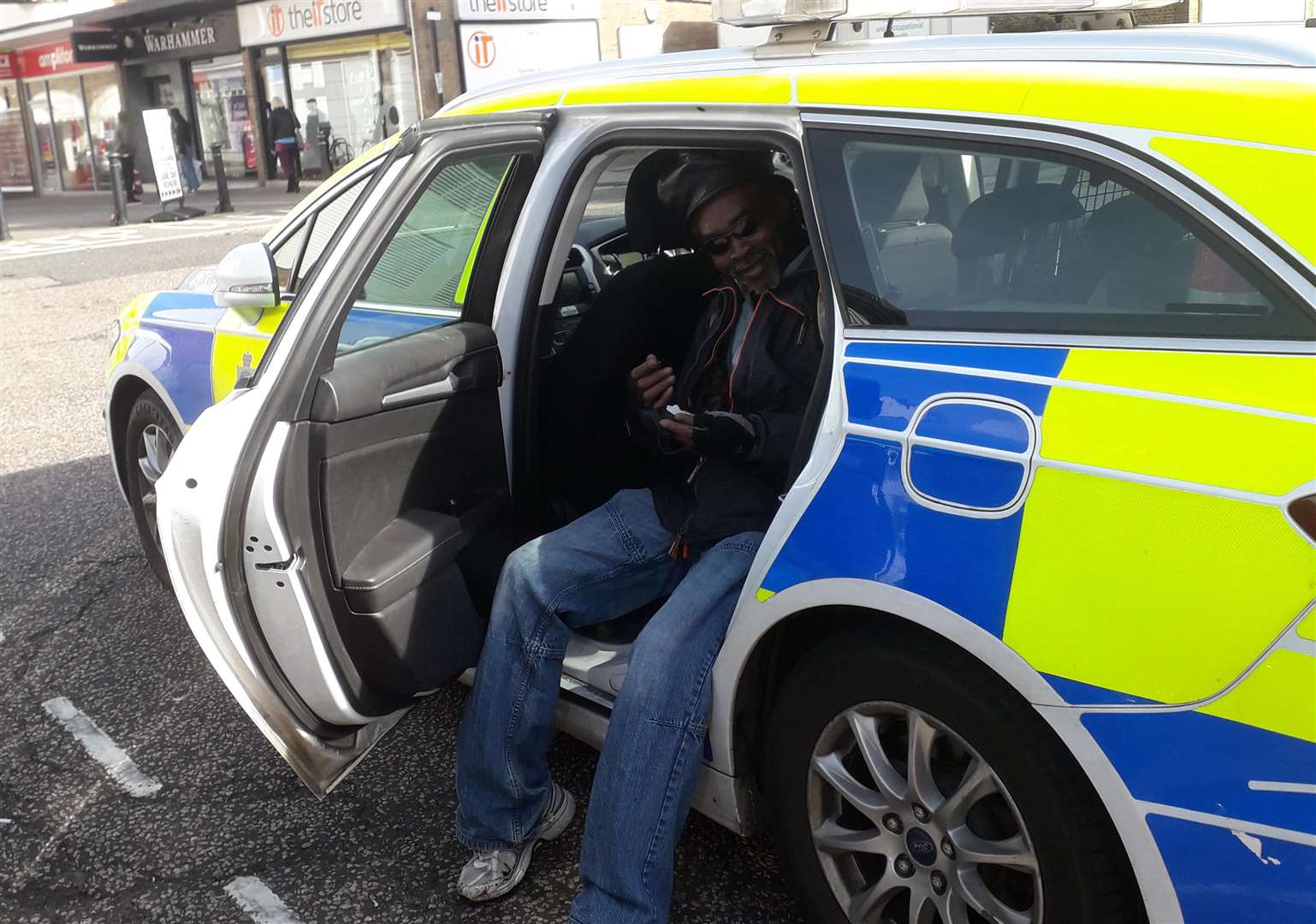 A passerby has a sit-down in the back of an unattended police car. Picture: Phil Martin.