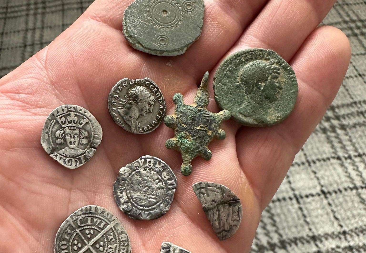 Various Roman and Medieval coins alongside a Saxon Disc brooch and a heraldic pendant found by Brendan