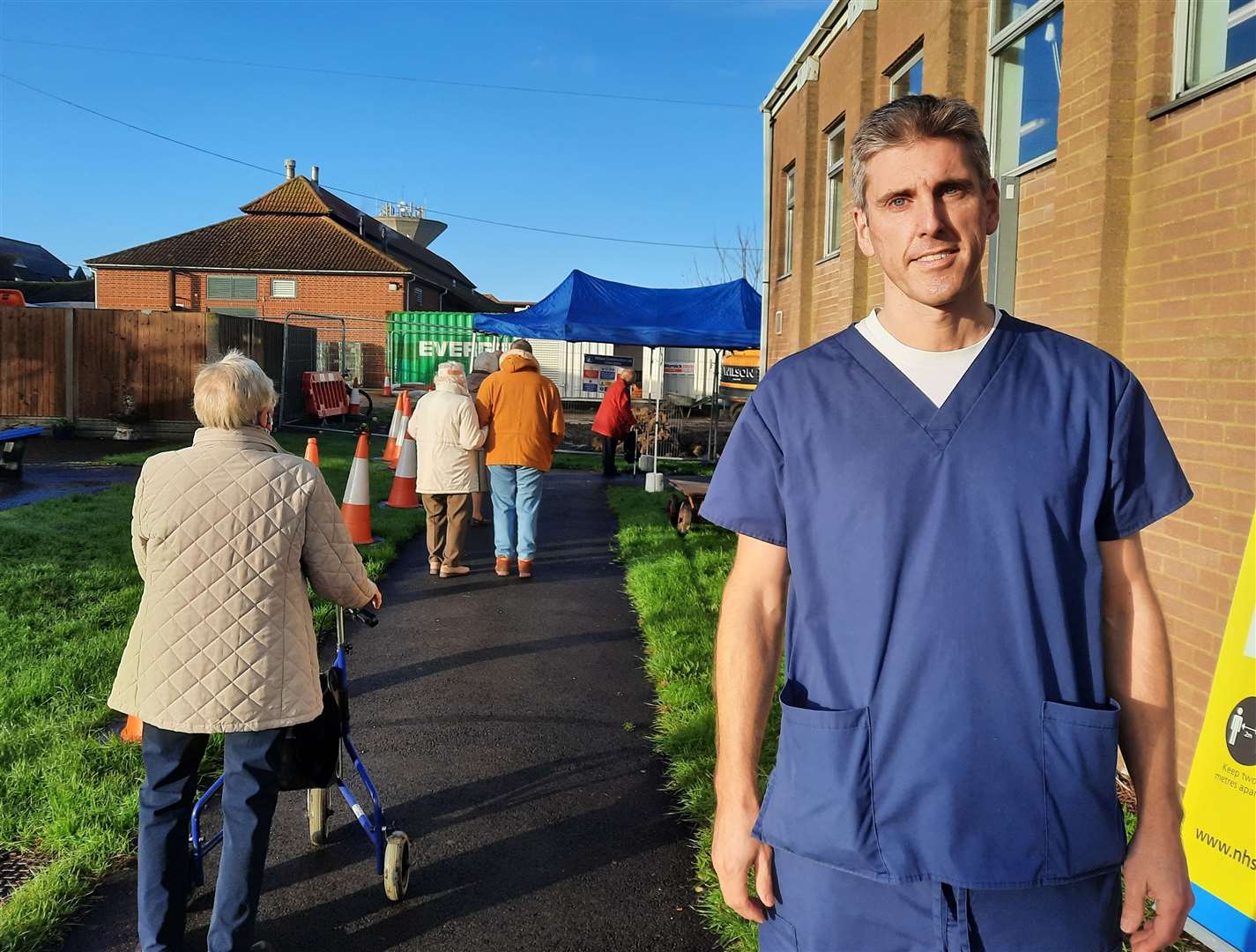Jeremy Carter stood next to the queue of people waiting for a vaccine