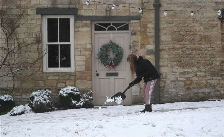 A woman clearing the snow from outside her home. (Steve Parsons/PA) (44304539)