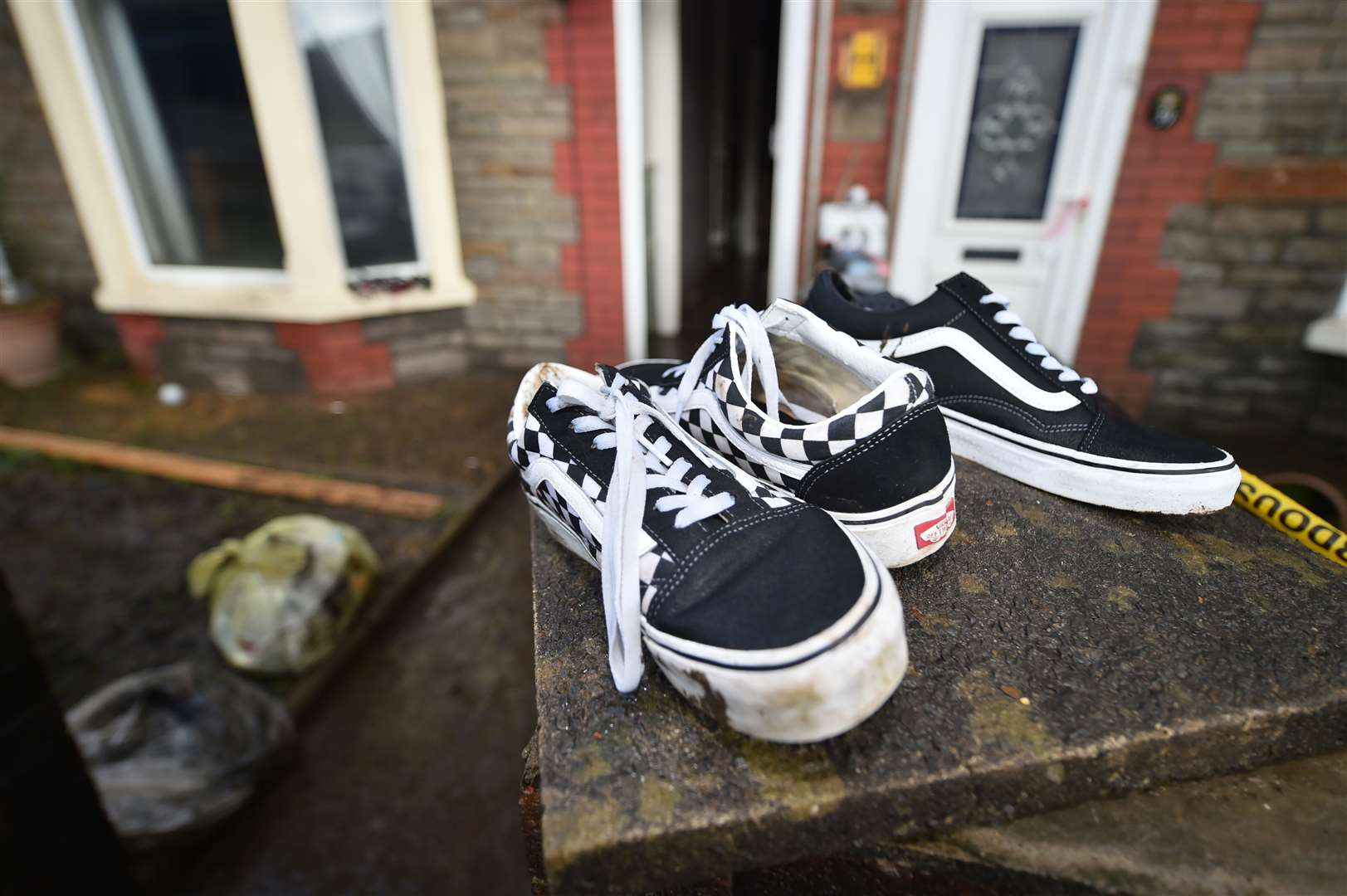 A pair of Vans trainers are left to dry out on a wall outside a property on Oxford Street, Nantgarw (Ben Birchall/PA)