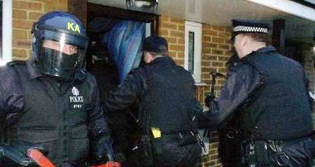 DAWN RAID: Police break down the door of one of the properties. Picture: PAUL DENNIS