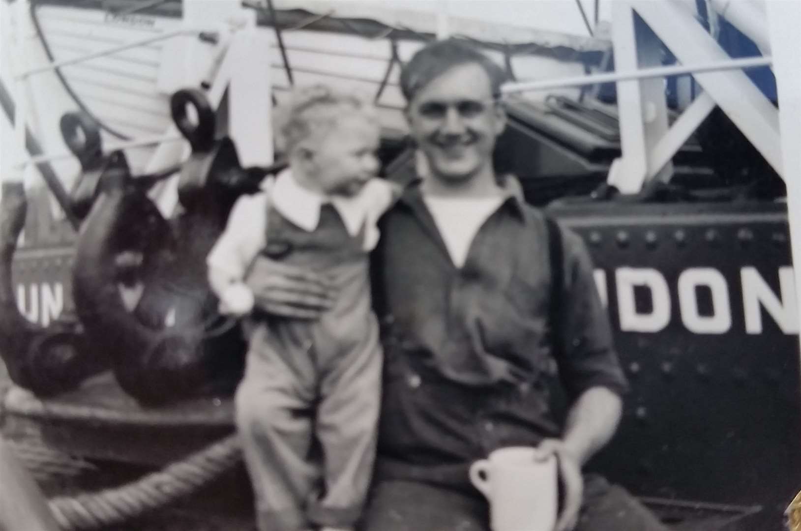 Dennis McCarthy on board one of the London Tugs he used to work on while holding his son Terry as a toddler