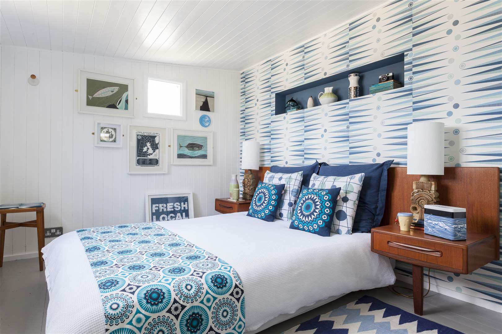 Bright blue fabrics inject personality into the couple’s white bedroom. The bed is another teak piece, found on eBay and cut down to fit the space.