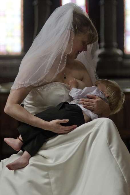 Wearing a wedding dress, Vicky breastfeeds Christopher, aged 20 months