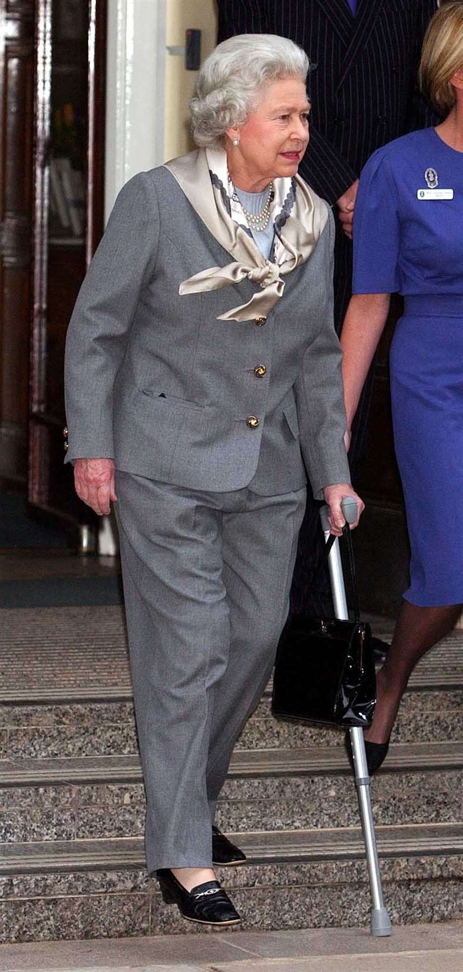 The Queen walks with a stick as she leaves King Edward VII’s Hospital after keyhole surgery in 2003 (John Stillwell/PA)