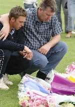 The murdered boy's brother, David, left, and father Lloyd read messages attached to floral tributes. Picture: ANDY PAYTON