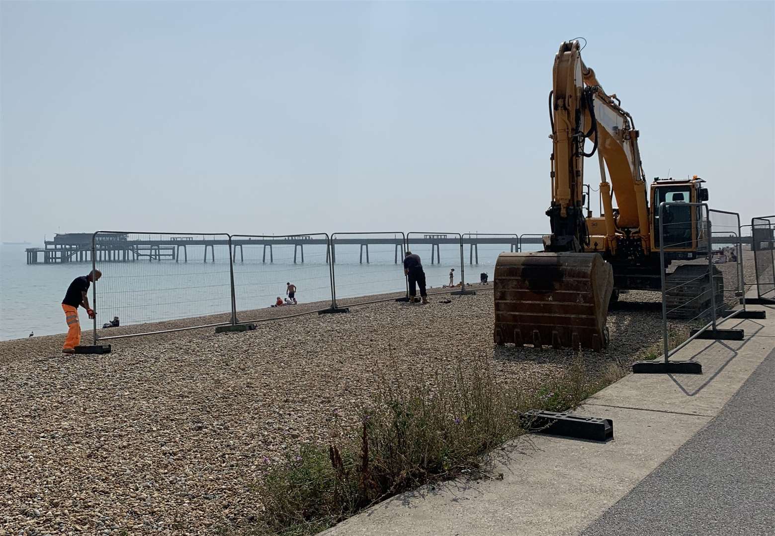 Workers installing a metal fence around the digger which arrived on Deal beach on Tuesday