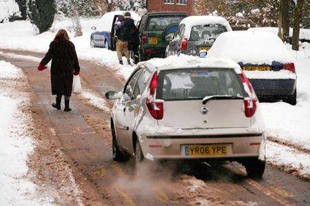 Pedestrian walks along Silver Hill on the road and makes the cars wait. Ashford continues under a blanket of snow.