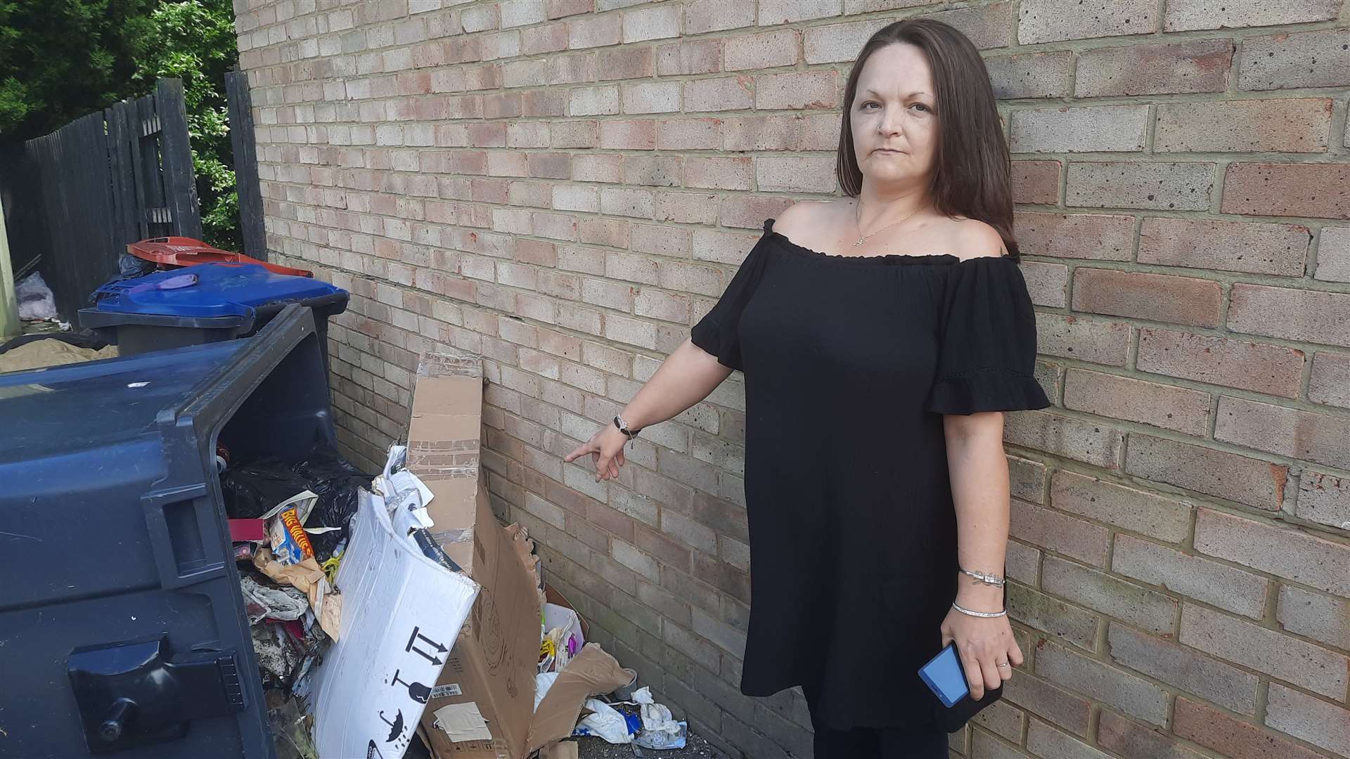 Canterbury resident Rachael Randall standing next to a tipped-over bin in the communal area