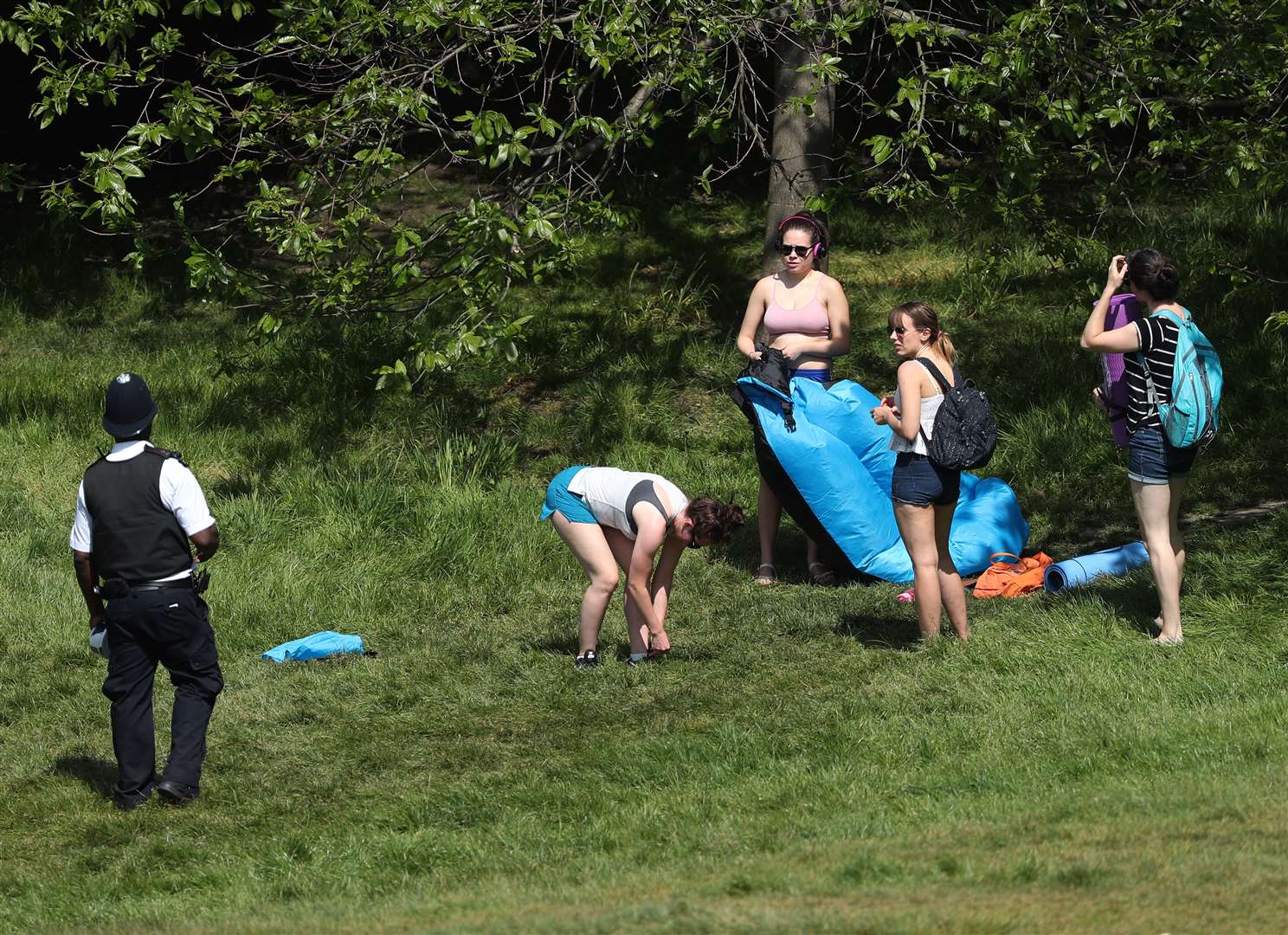A police officer moves sunbathers on in Greenwich Park, London (Yui Mok/PA)