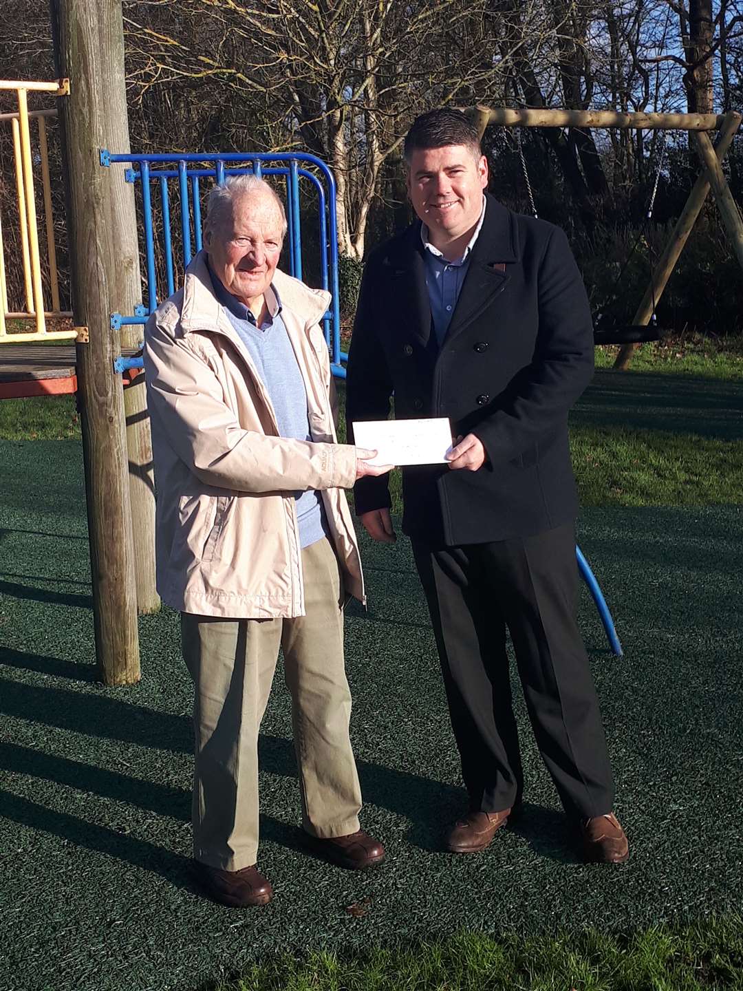 Gary Thomas accepting a donation from Dave Byford of the Kent County Playing Fields Association towards the village play area