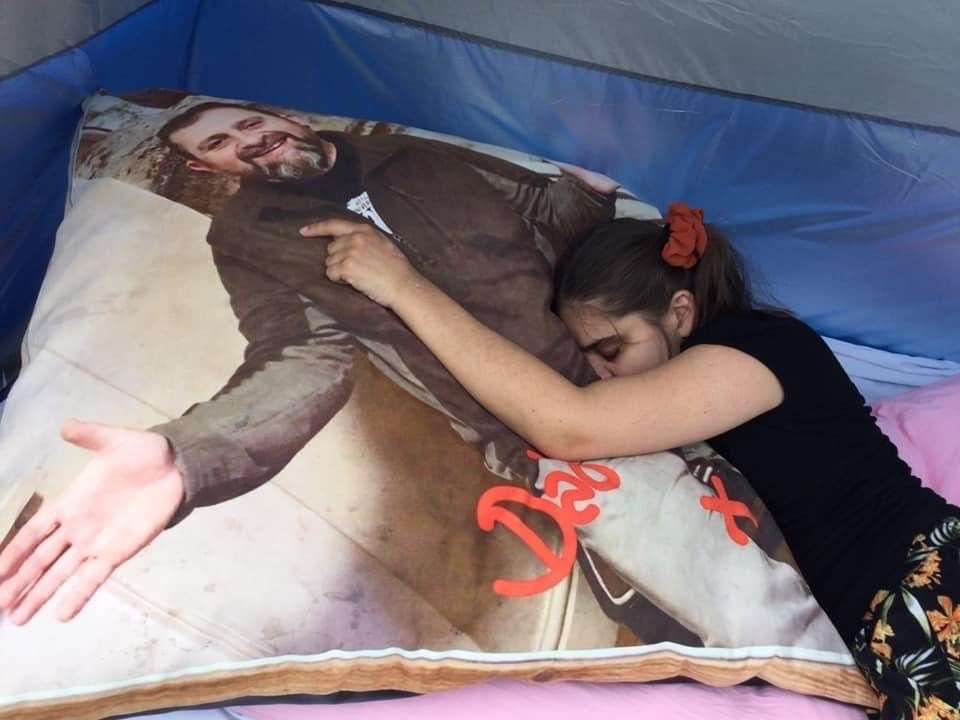 Charlotte hugs a pillow with an image of her dad Brett on it