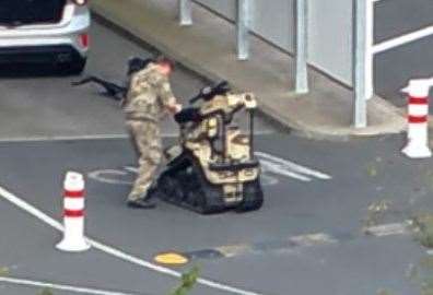 An Army explosive expert operates a specialist bomb disposal robot to search a silver car in a security lane. Pic: UKNIP