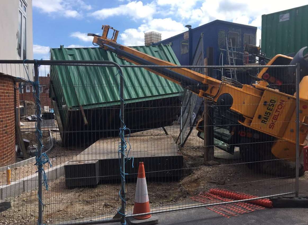 A crane moving a steel unit tipped over and took a chunk out of a house under construction.