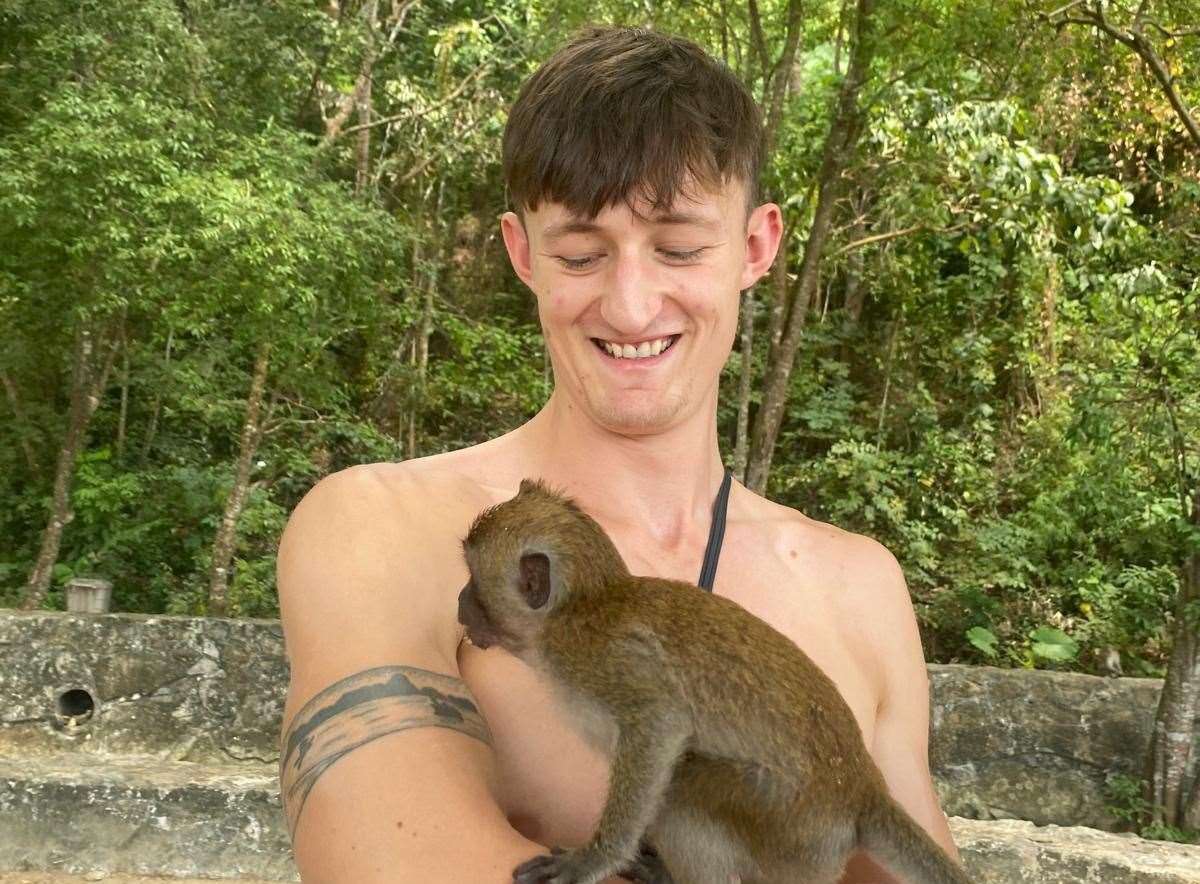 Josh Jones, 21, with a monkey during a holiday. Picture: SWNS