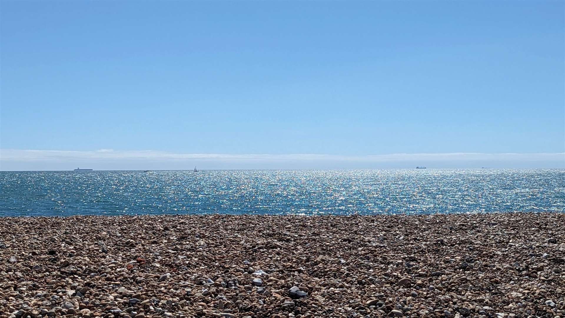 The waters of the English Channel shimmer beyond the shingle