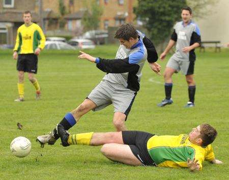 A Millfield player (yellow) puts a challenge in on an opponent from Queen Victoria in Division 3