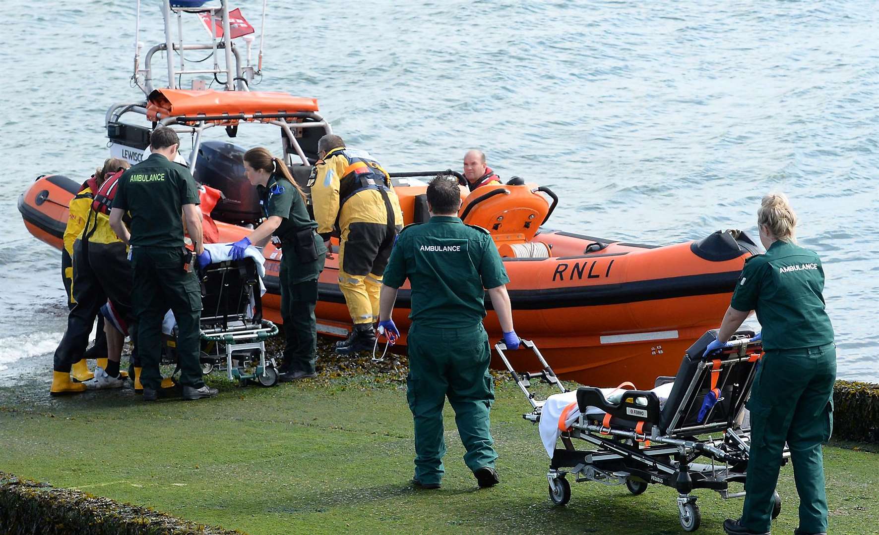 Emergency services helping the two men after they were pulled from the sea