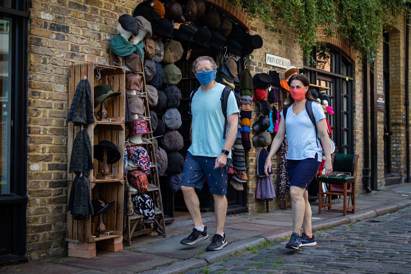 Two people wearing face coverings walk past a shop in Camden Market (Aaron Chown/PA)