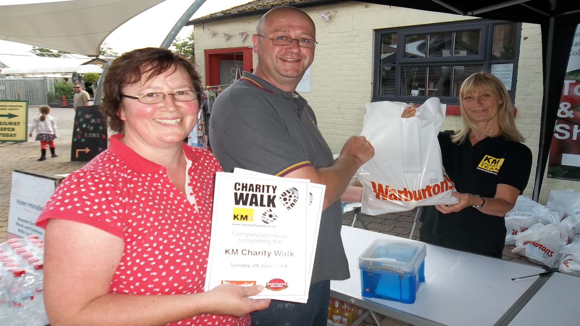 Sarah and Mark Longstaff of Maidstone receive their certificates and Warburtons goody bags from Louise Rogerson of KM Charity Team having successfully completed the KM Charity Walk 2014