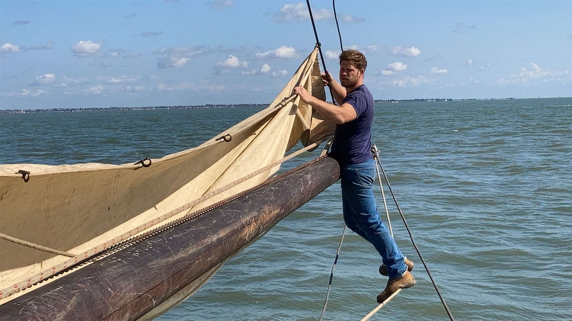 Ed Gransden balancing precariously on the bowsprit of the Thames sailing barge the Edith May as it sets sail from Sheppey