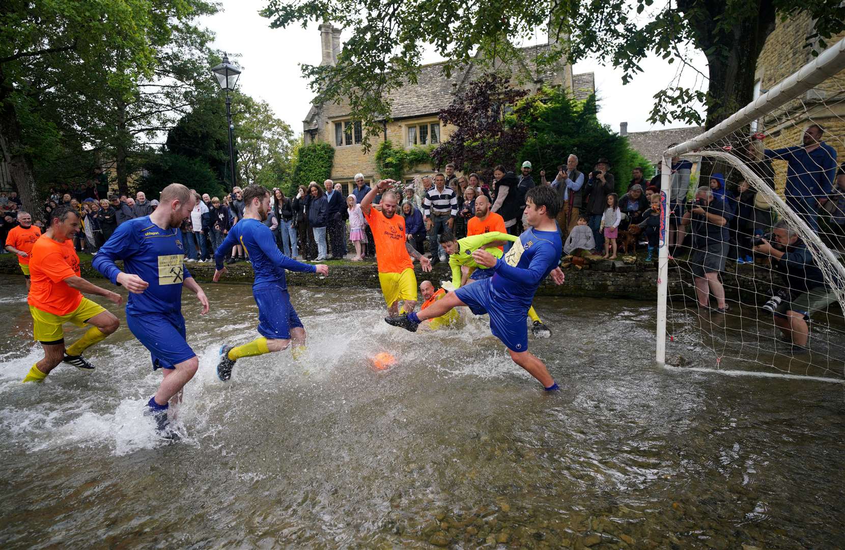 Players challenge for the ball during the annual traditional River Windrush football match, which has been taking place for more than 100 years, in the Cotswolds village of Bourton-in-the-Water, Gloucestershire, in August (PA)