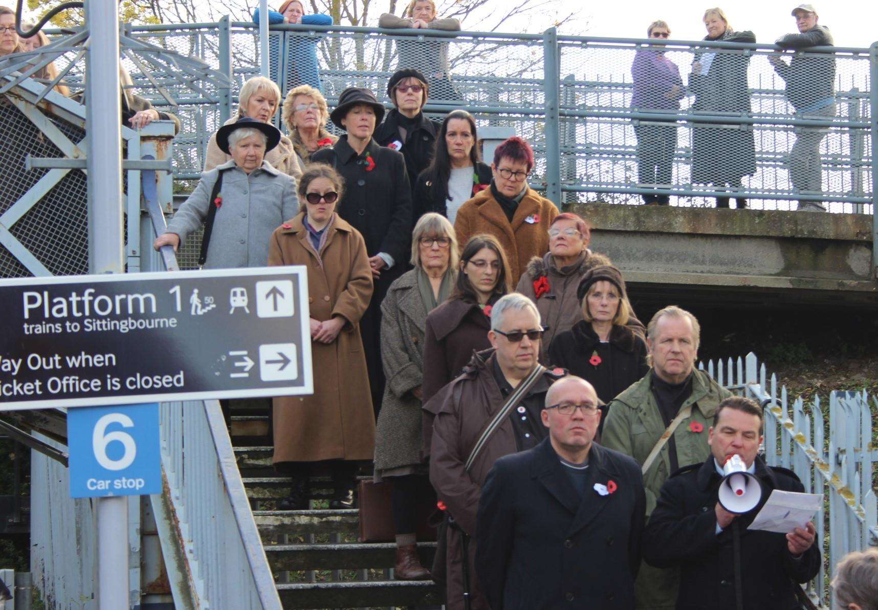 Bridge over troubled waters: Tania Holland-Williams, left, and Emily Peasgood and the 55-plus choir at Queenborough train station on Sunday performing Never Again. Picture: John Nurden (5337051)