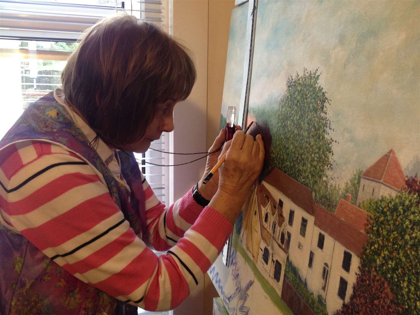 Dawn Parkinson uses a magnifying glass to help her paint