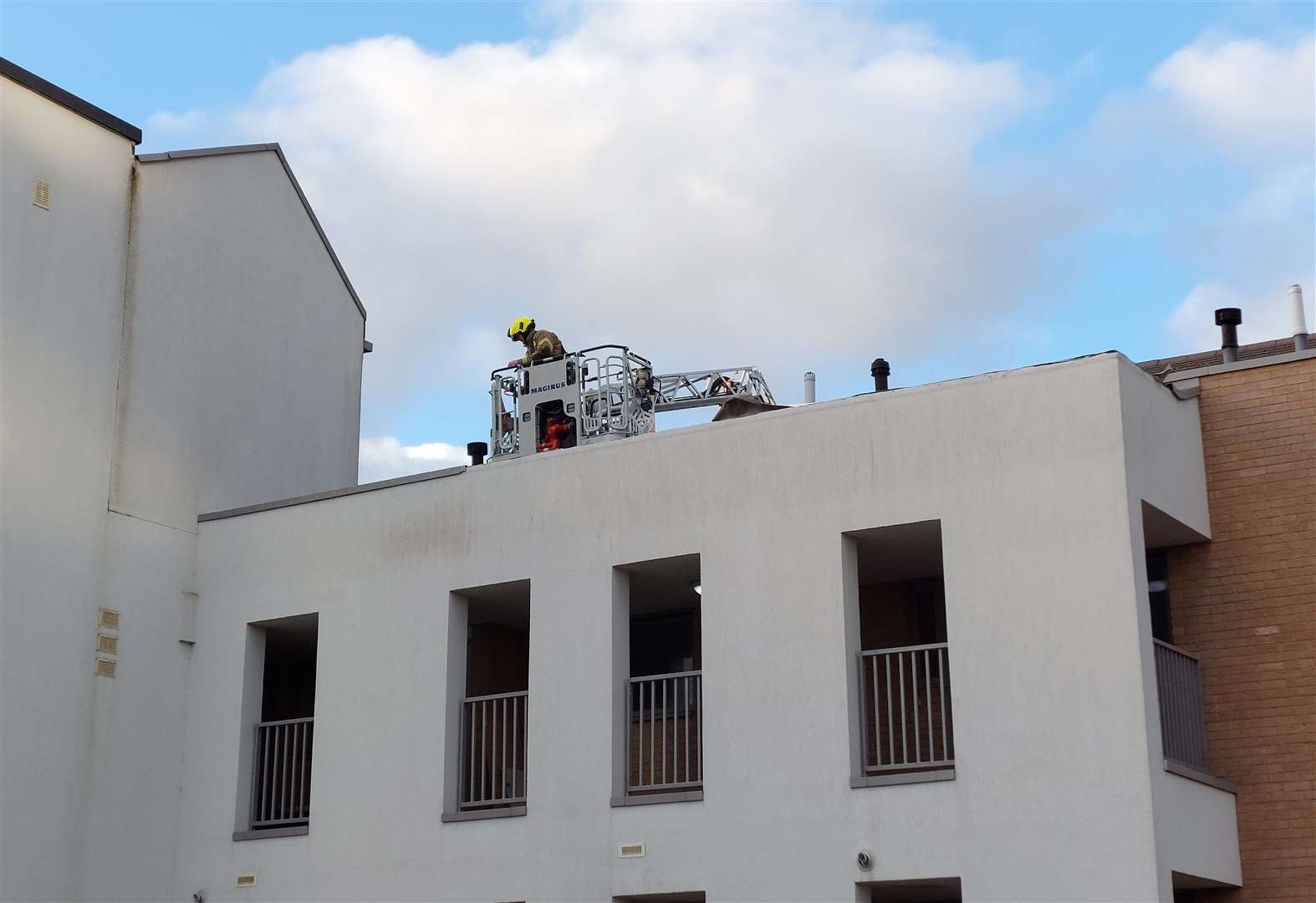 A firefighter removes tiles from the roof of Bakers Court on Friday