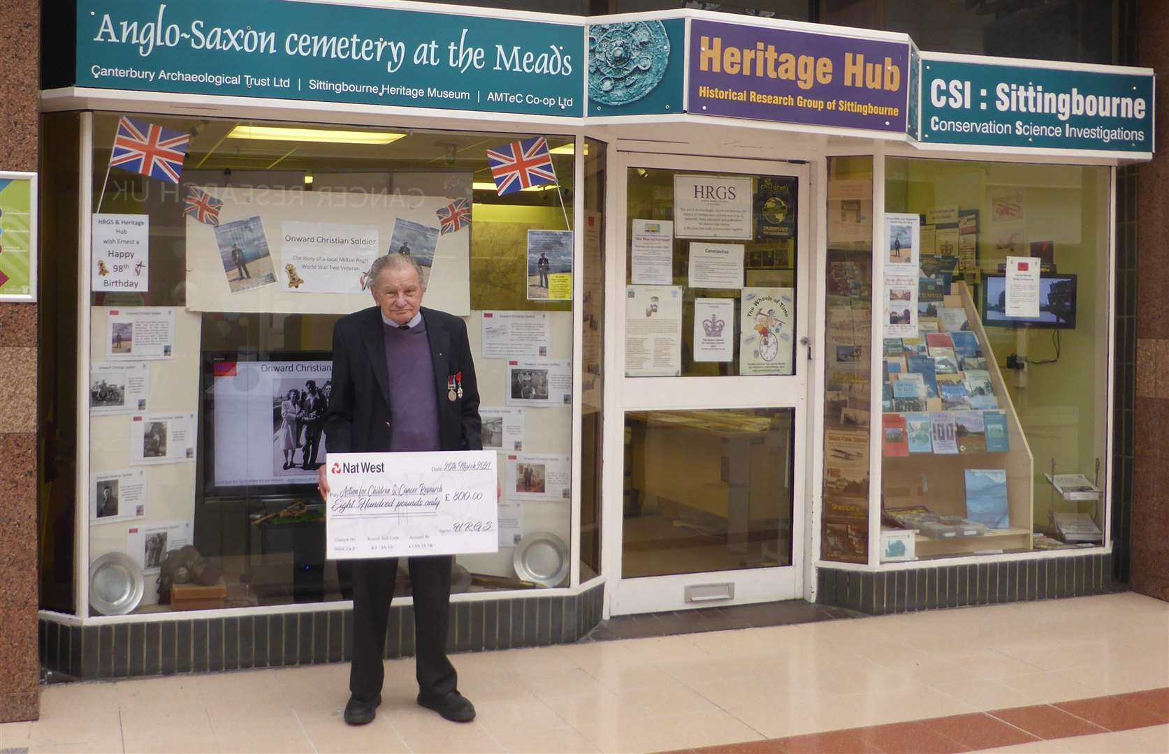 Ernest Slarks outside the Heritage Hub in Sittingbourne on his 98th birthday, with a cheque for charity from the proceeds of his memoir about the Normandy landings