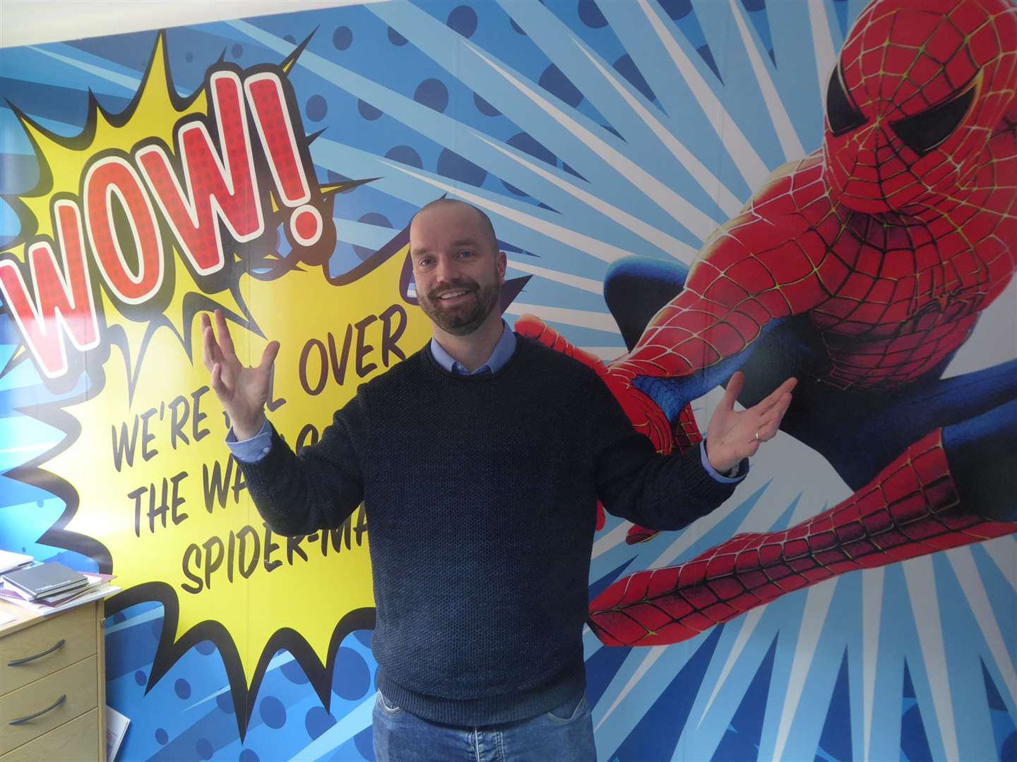 Buckland Media Group production and customer service manager Richard Archer in front of a superhero-themed mural created by the company (12563270)