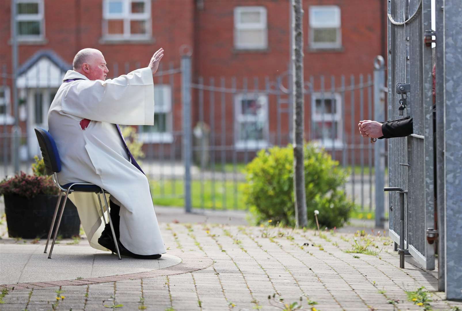 Fr Paddy McCafferty resumed hearing confessions in May while observing social distancing through the locked gates of Corpus Christi Church in Ballymurphy, West Belfast (Niall Carson/PA)