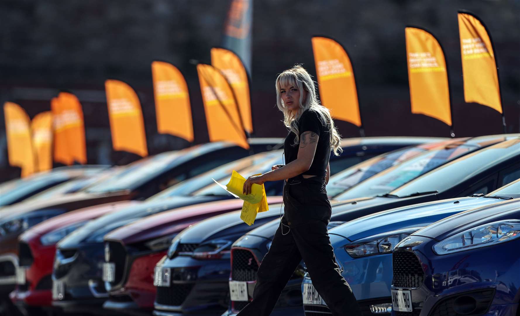 Staff at Arnold Clark in Liverpool walk past cars on the forecourt as showrooms opened for the first time since the lockdown in England (Peter Byrne/PA)