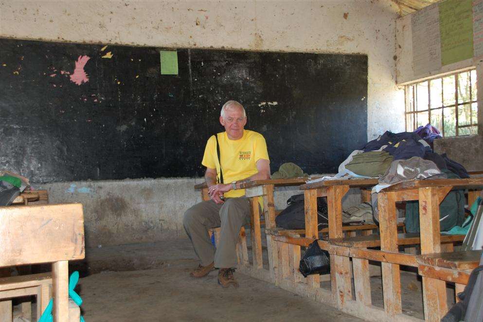Dave Anderson sitting in one of the classrooms at Marula where there is a large hole in the floor and broken windows as there's no money for maintenance